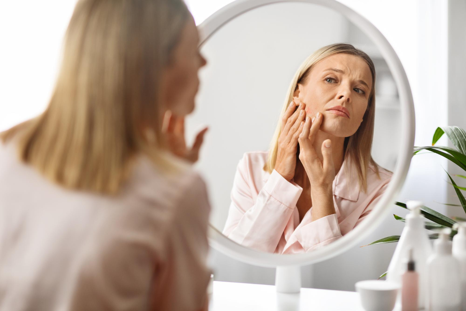 Woman in her 30s examining hormonal acne in the mirror during a skincare routine