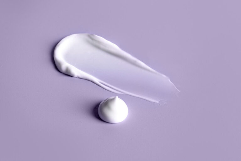 White azelaic acid cream texture on purple background for hormonal acne treatment