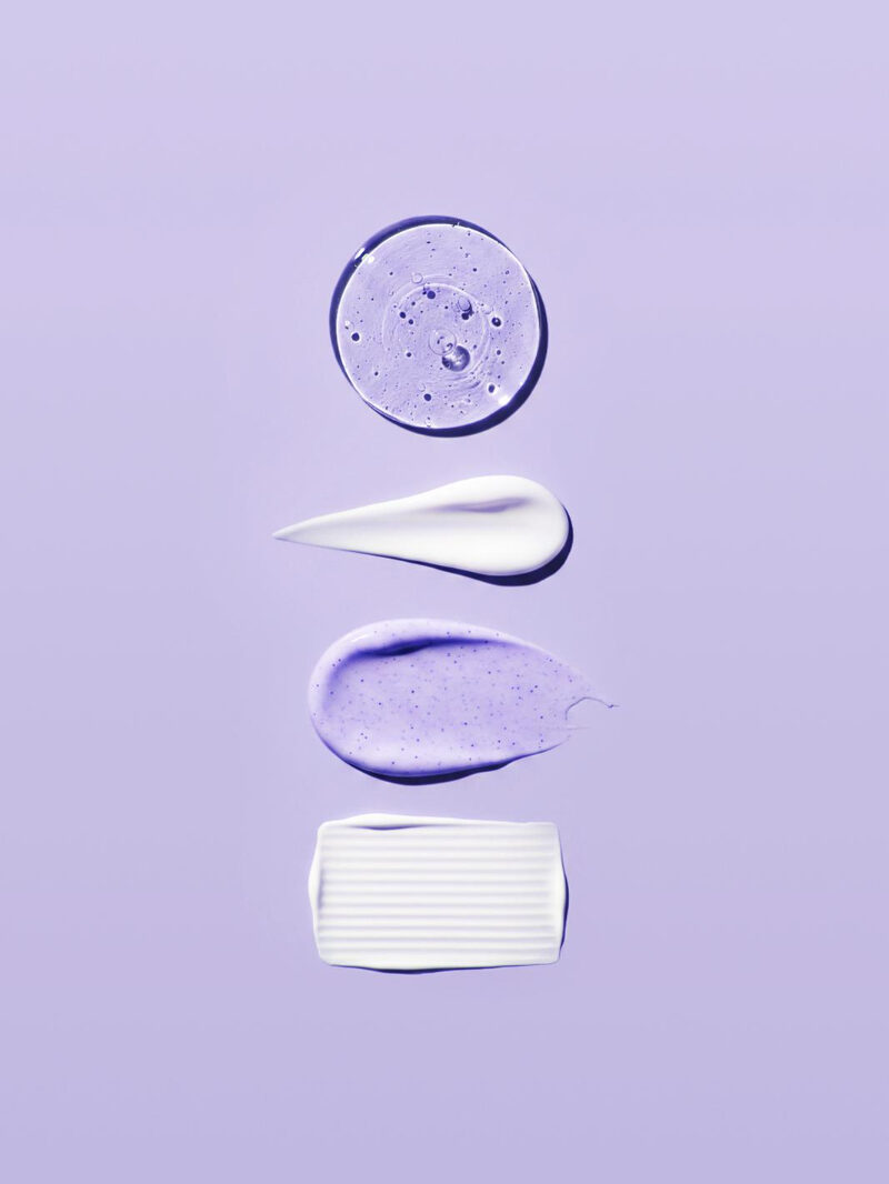 Skincare product textures on purple background — serums, creams and balms for hormonal skin
