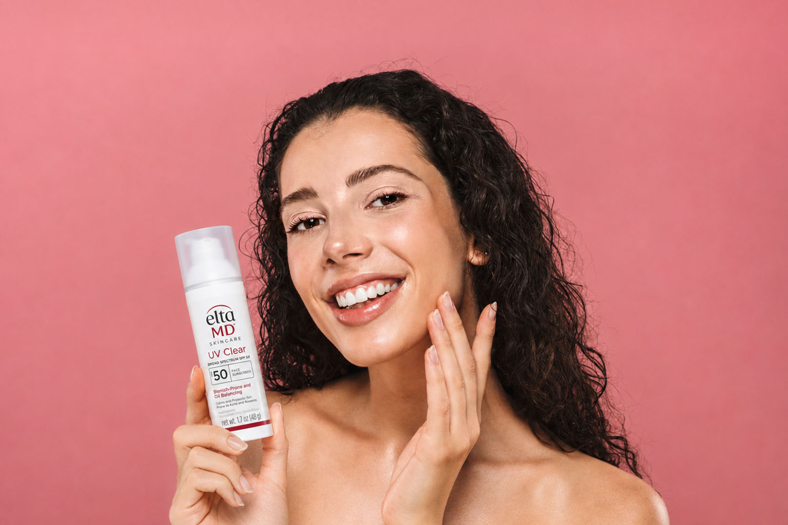 Woman holding EltaMD UV Clear sunscreen for hormonal acne