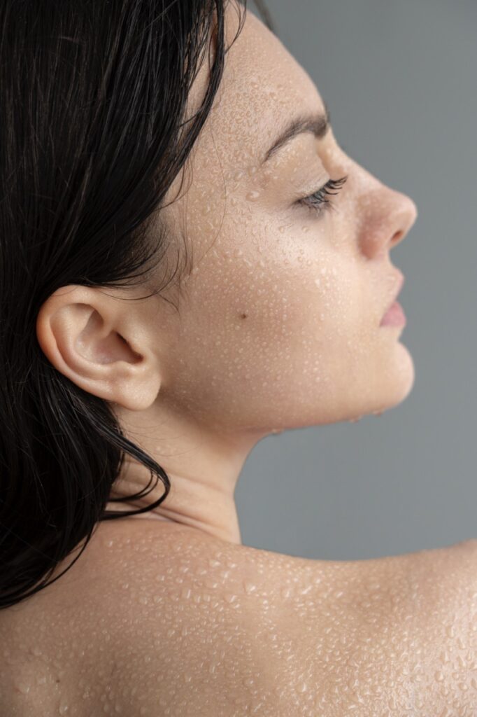 Woman with water droplets on damp skin showing how to apply hyaluronic acid correctly