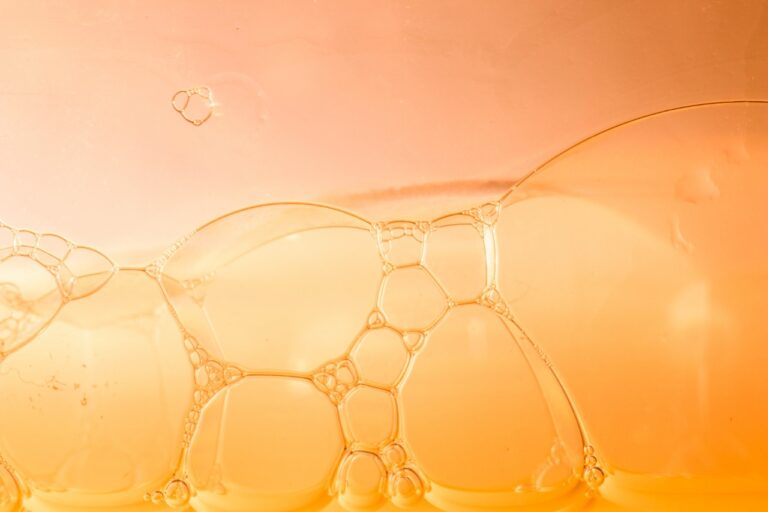 Golden vitamin C serum texture with bubbles representing brightening skincare