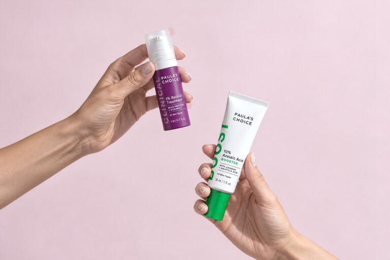 Hands holding a 1% retinol and a 10% azelaic acid serum, the two products in this skin care routine.