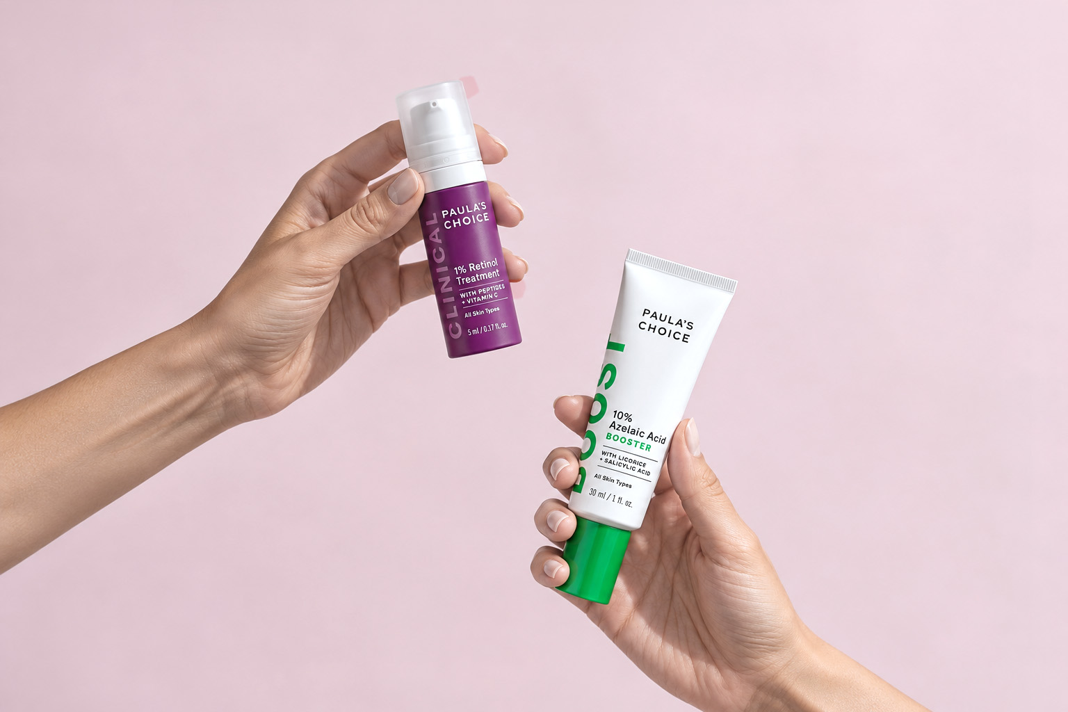 Hands holding a 1% retinol and a 10% azelaic acid serum, the two products in this skin care routine.